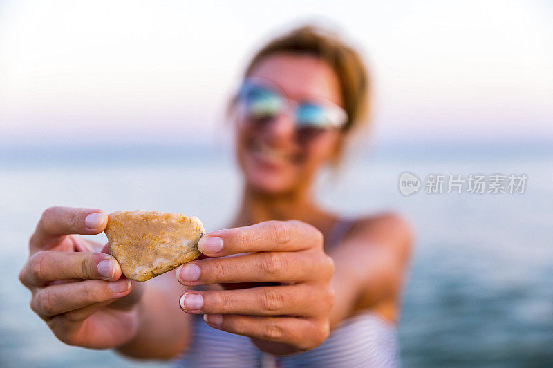 在海滩上拿着石头的女人