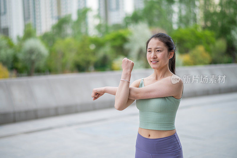 年轻的亚洲女子在城市公共广场练习瑜伽