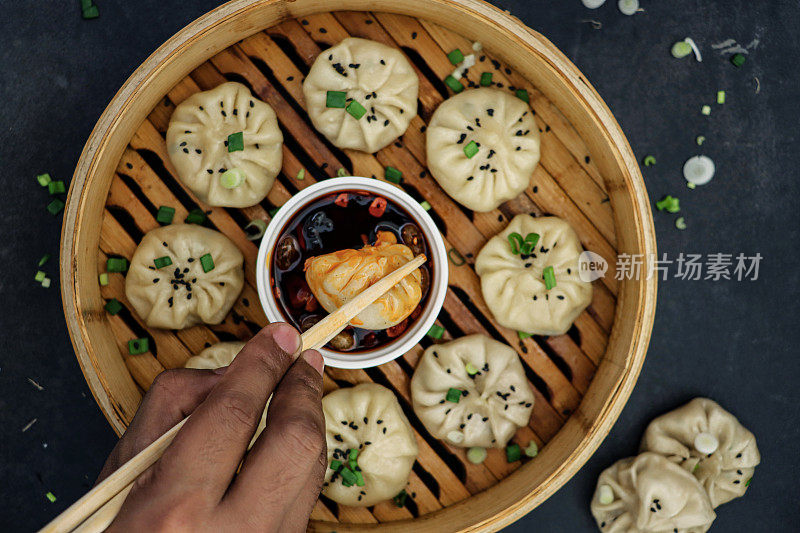 让人难以辨认的人用筷子，蒸笼里蒸出的馍馍(南亚饺子)，白面和猪肉馅的水面团和混合蔬菜蘸着辣椒油蘸酱的小模子，景色优美