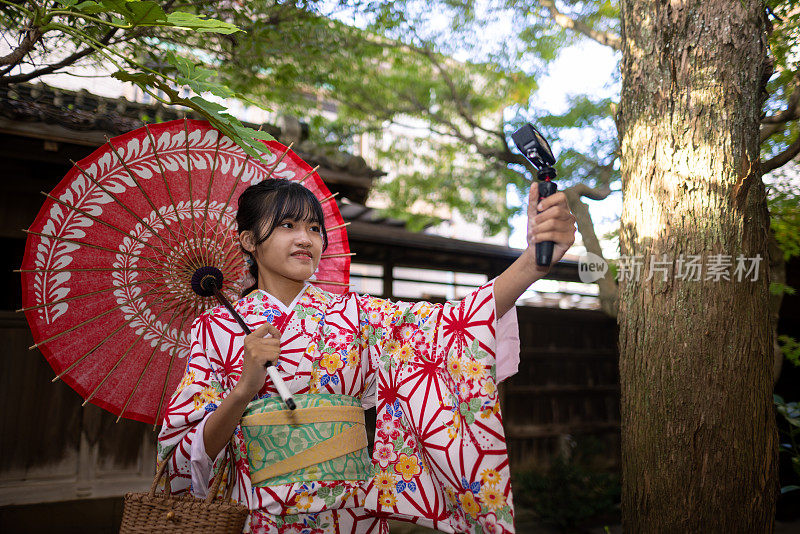 穿着和服打着纸伞的少女在传统的日本房子里拍视频