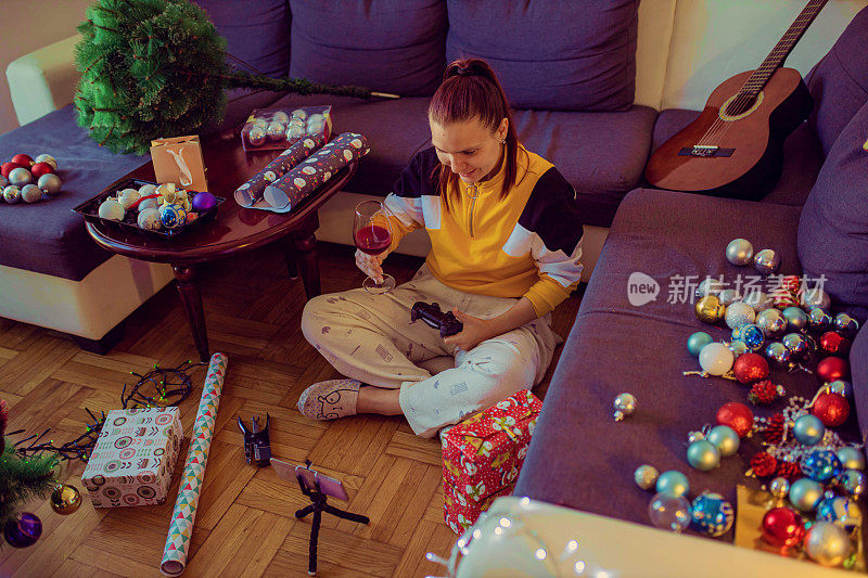 快乐的女人和她的男友通过视频电话庆祝新年，喝着红酒，玩着电子游戏