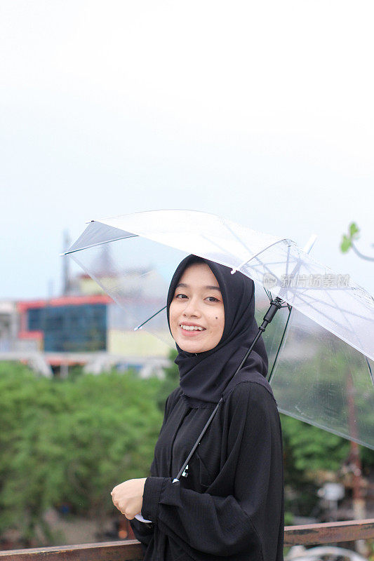 快乐的亚洲女人撑着伞站在城市公园里