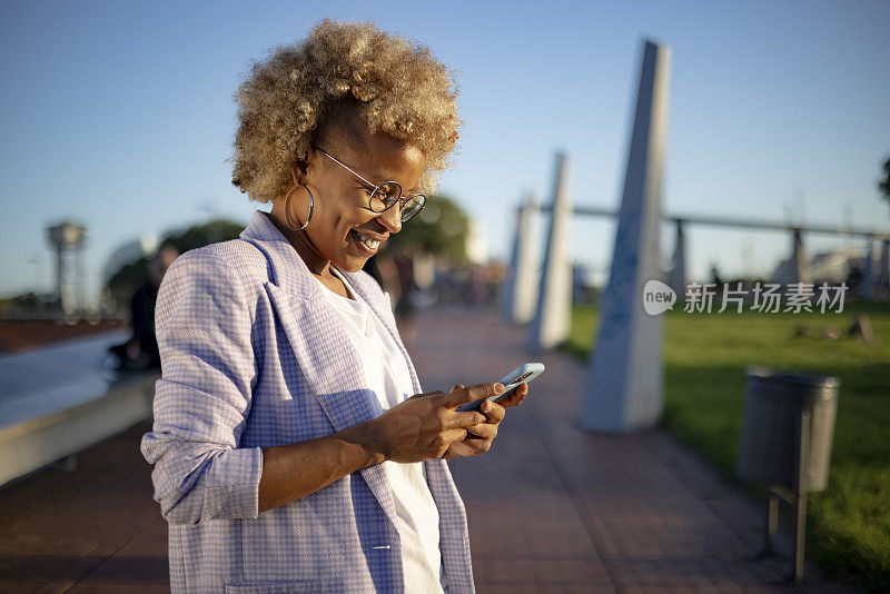 年轻的西班牙裔黑人女性在户外使用智能手机