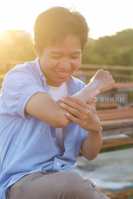 年轻人坐在户外使用防晒霜护理