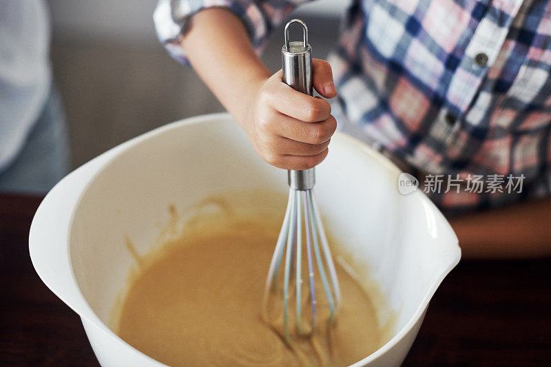 一个不知名的女孩在家里搅拌原料和烘焙