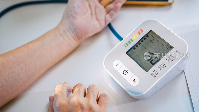 老年人检查血压，在家里的笔记本上记录血压数字。