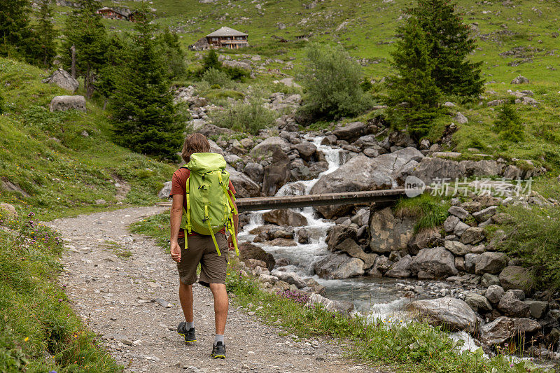 年轻人在美丽的高山风景中徒步旅行，夏天在瑞士的阿尔卑斯山漫步，享受大自然和户外活动