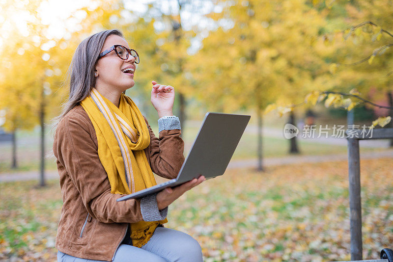 在公园里拿着笔记本电脑的女人