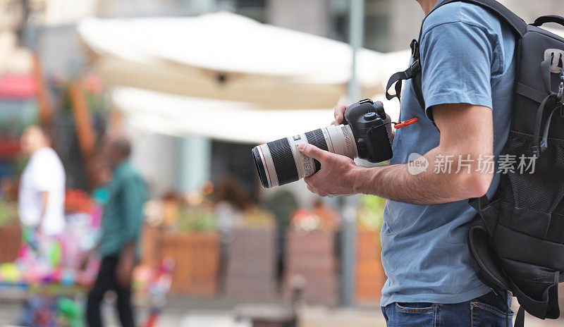 摄影师在城市里用数码单反相机拍照。