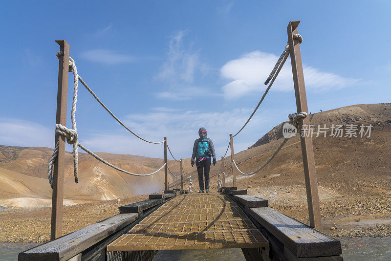 一名妇女在Hveradalir地热区过桥