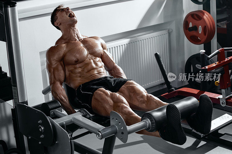 肌肉发达的男士在健身房做腿部锻炼，强壮的男士四头肌锻炼锻炼
