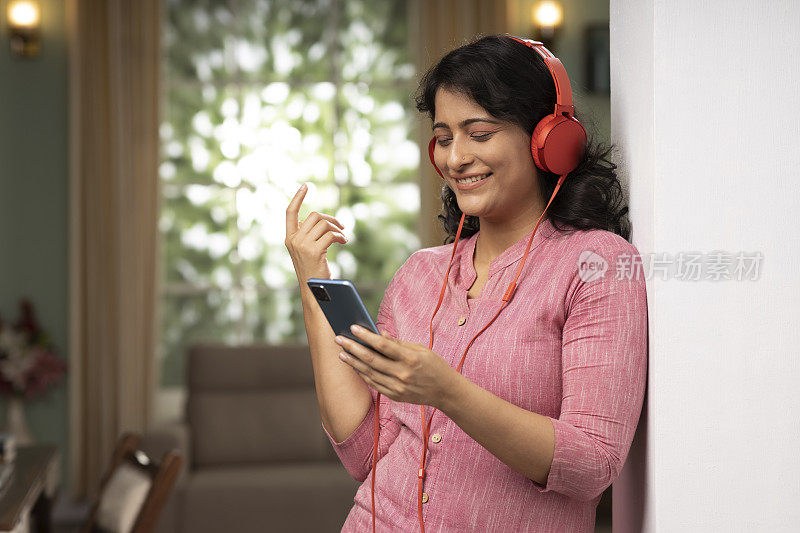印度女人在家听音乐股票照片