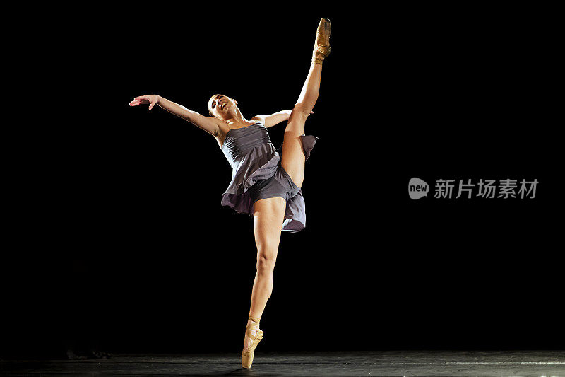 女孩在黑暗的舞台上跳新古典芭蕾