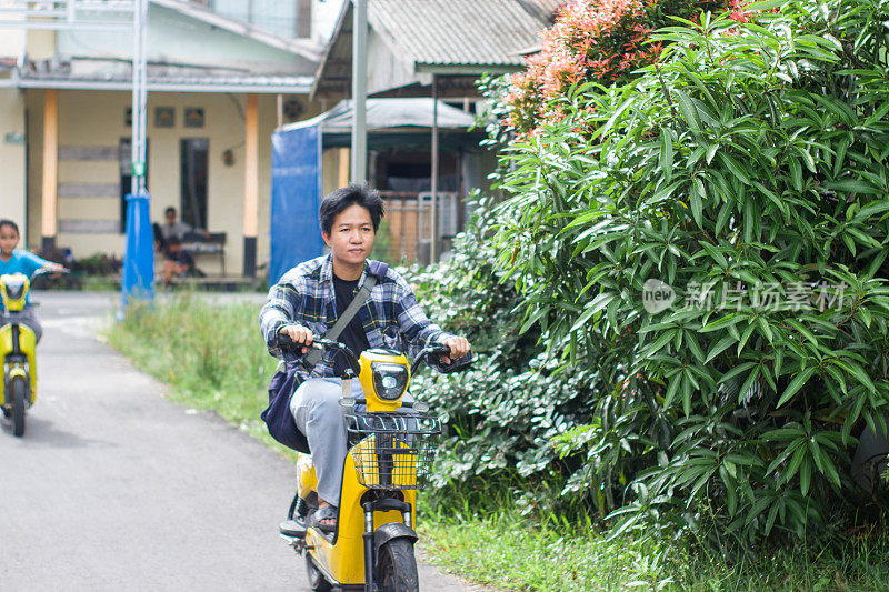 男孩和弟弟在小区骑着电动车，一起出去玩