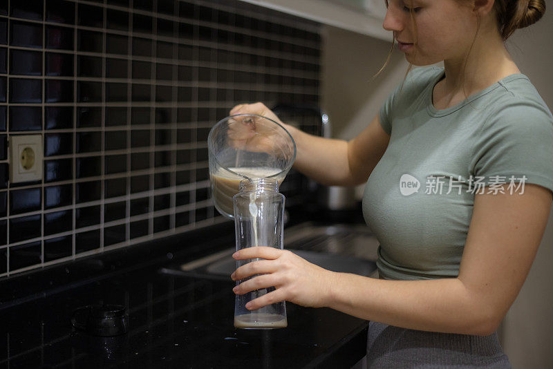 年轻女子在厨房准备运动饮料。