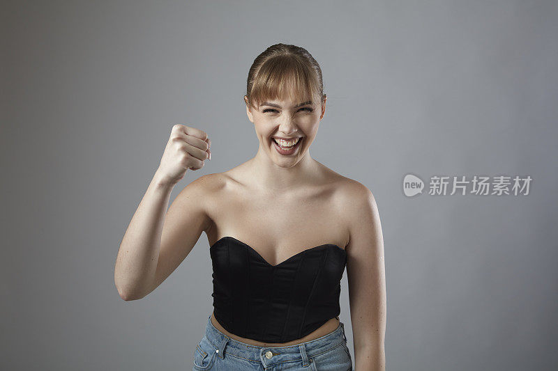 年轻的金发女人与刘海微笑显示她的拳头。