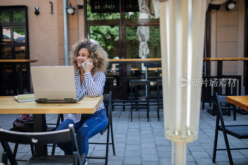 漂亮的年轻女子留着非洲式发型，正在咖啡馆用笔记本电脑工作。