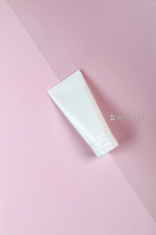 白色挤压瓶塑料管的模型，用于药品或化妆品的品牌-面霜，凝胶，护肤品，牙膏。化妆品瓶容器在粉红色的背景。极简主义