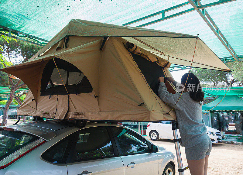 年轻女子，爬上梯子到车顶上的帐篷，小睡一会儿。