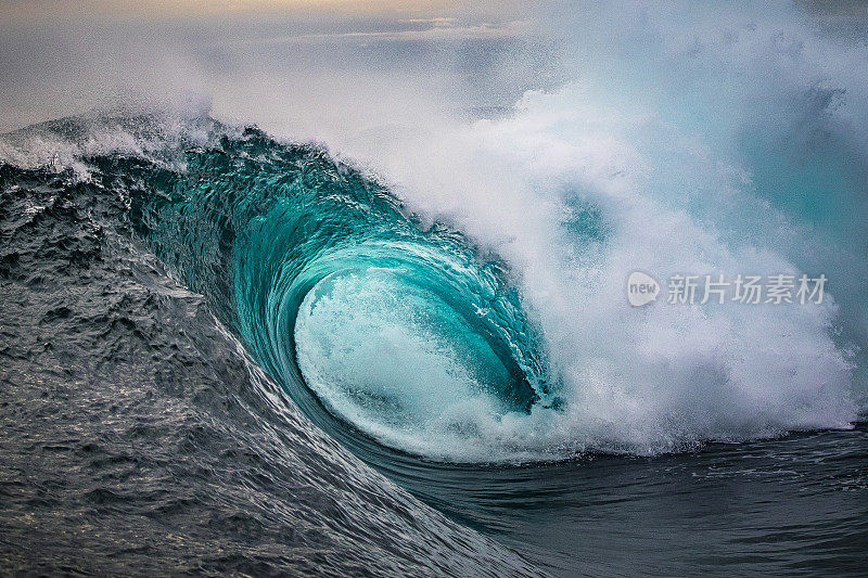 在金色的光线下，巨大的海水海浪在浅滩上猛烈地破碎