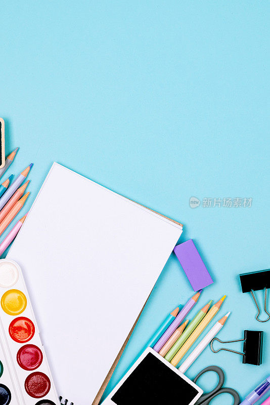 蓝色背景的学校笔记本和各种文具。