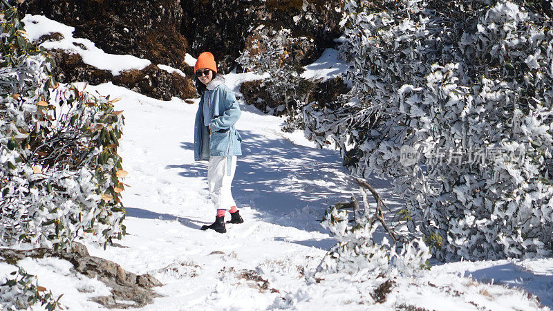 一个女人在寒冷的天气里穿行于白雪覆盖的山林之中