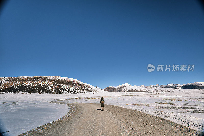 冬天，女游客走在空旷的路上，在高原上看风景