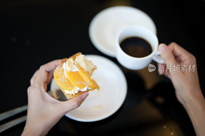 在舒适的咖啡馆里，一位女士享用着桃子馅饼配上一杯浓郁的黑咖啡，这是完美的餐后享受