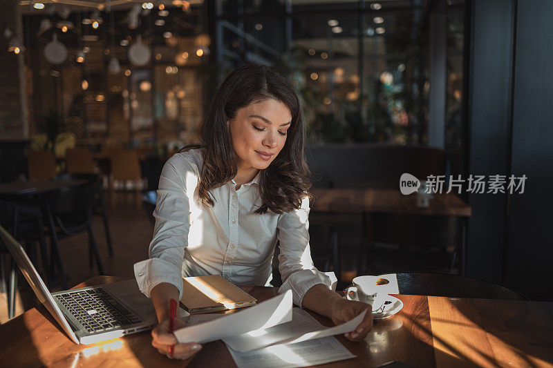 一位美丽的女商人坐在咖啡馆里，用笔记本电脑享受着她最喜欢的咖啡