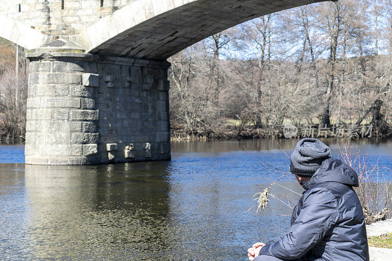 一个孤独的人坐在河边，