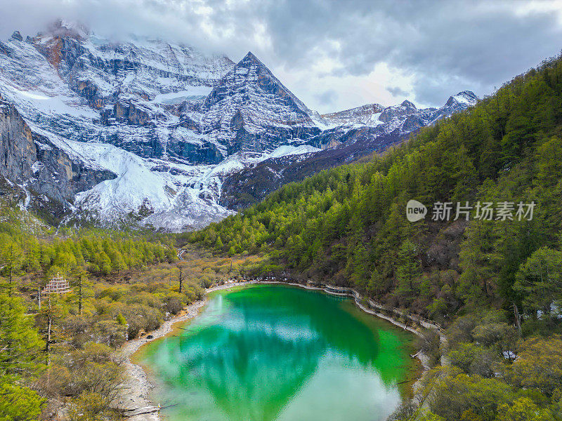 中国亚丁自然保护区无人机鸟瞰图。白雪皑皑的陈若芝风景如画，四周环绕着常绿的树木和湖泊