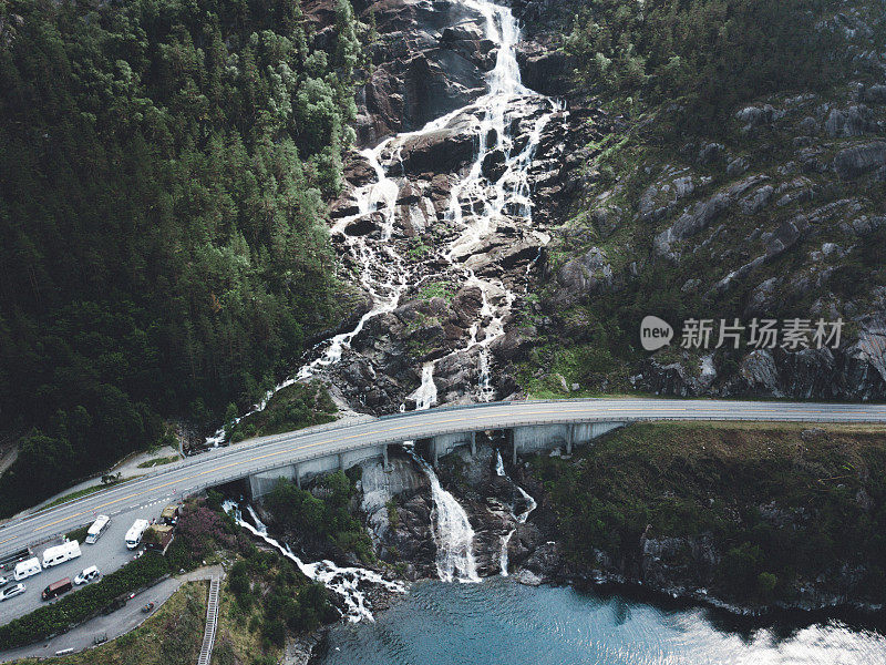 鸟瞰图，巨大的瀑布落入挪威的绿松石湖和道路