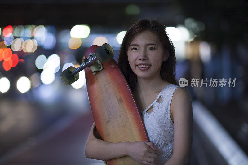 年轻女子拿着她的滑板和微笑
