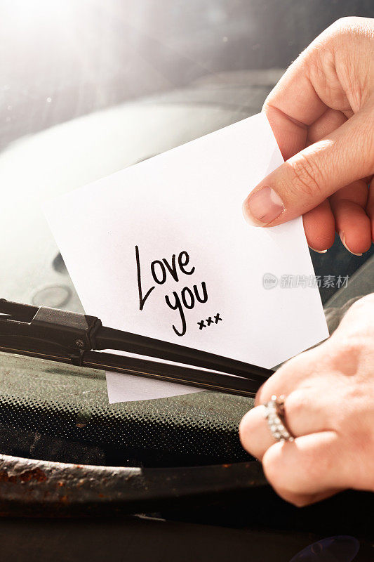 女性将写有“爱你”的纸条放在雨刷下