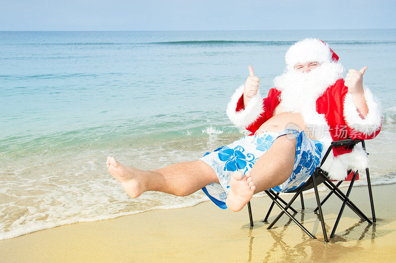 海滩上穿着短裤的有趣圣诞老人。