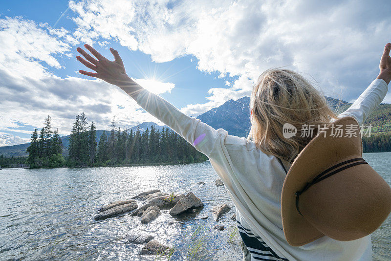 年轻女子在湖边伸开双臂