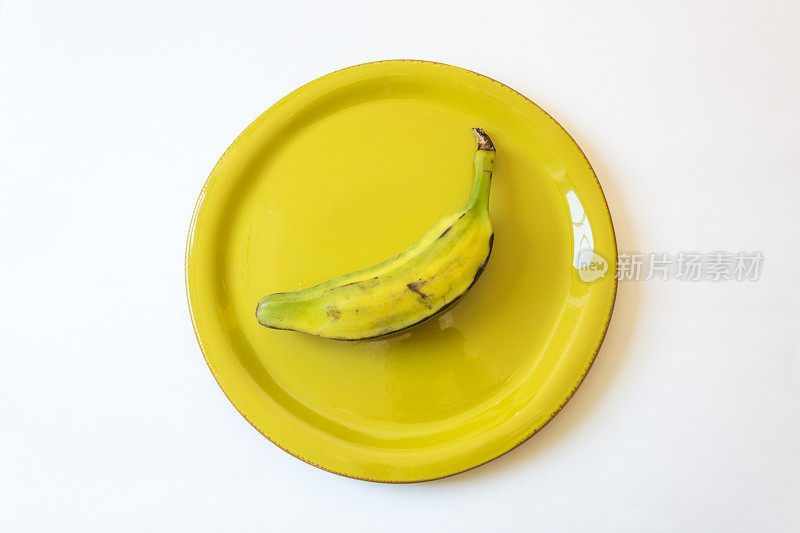 半熟的毛驴香蕉放在鲜绿色的盘子上，也可以是奥里诺科，布卢格，马，猪或拉戈香蕉，单独放在白色的盘子上