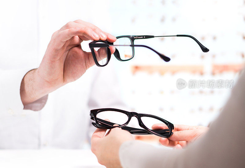 验光师送新眼镜给顾客试用。眼科医生在眼镜商店给病人展示隐形眼镜。
