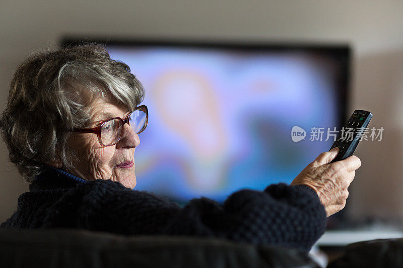 老妇人拿着电视遥控器