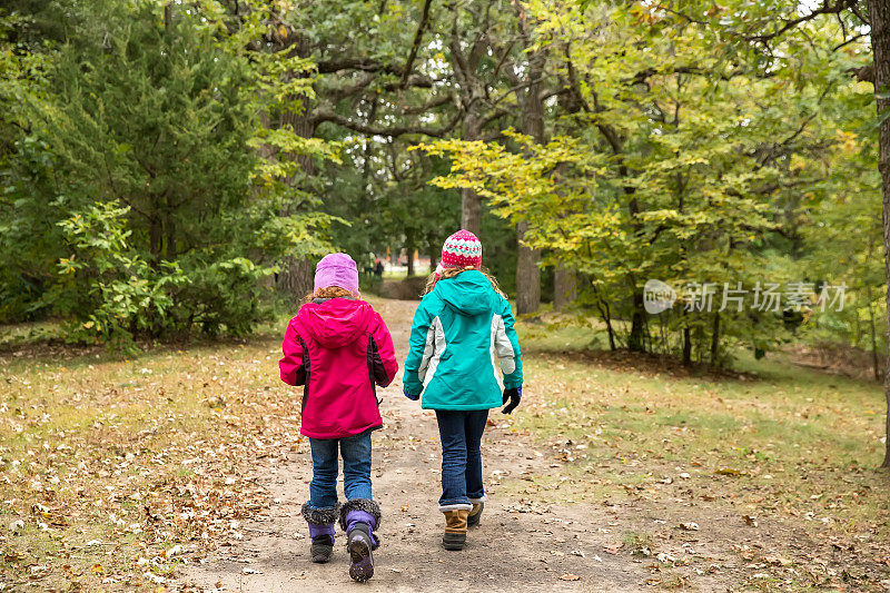 秋天里穿过树林的两个女孩