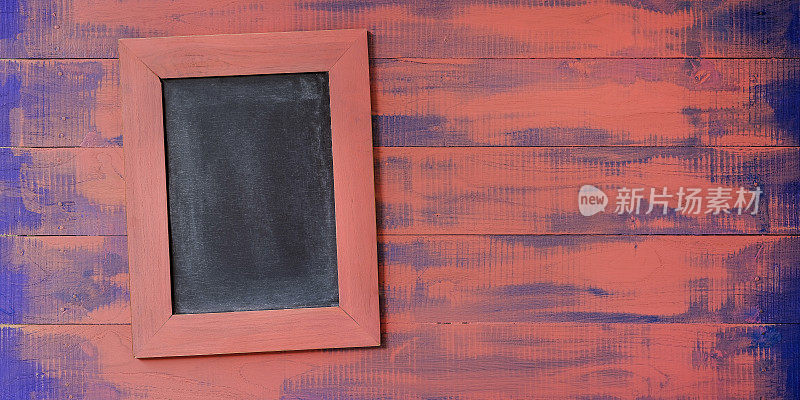 抽象的亮粉色和蓝色的老木面板背景，以粉色的木框黑板斜挂在背景上，图像右侧有大量的复制空间，色彩为2019年主题。
