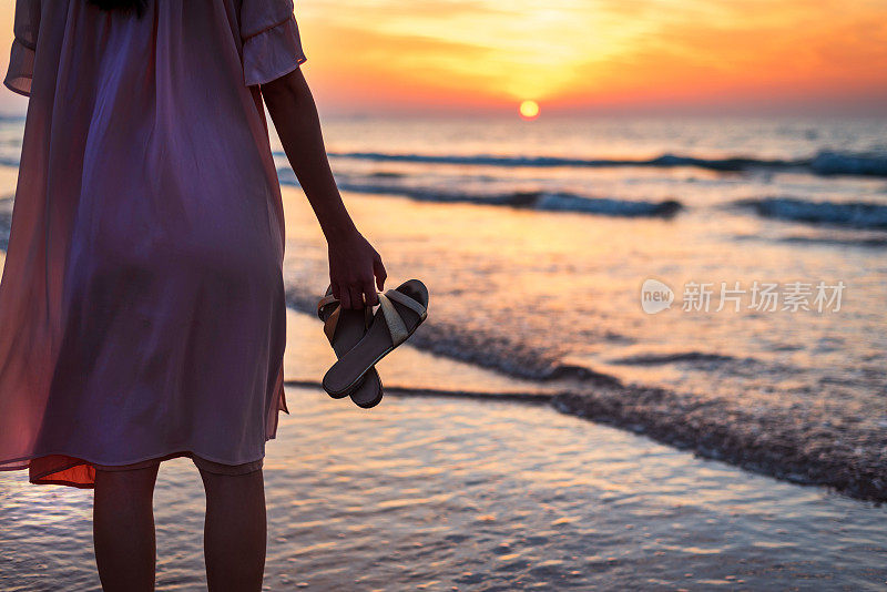 女人面对浪漫的日落在海滩上