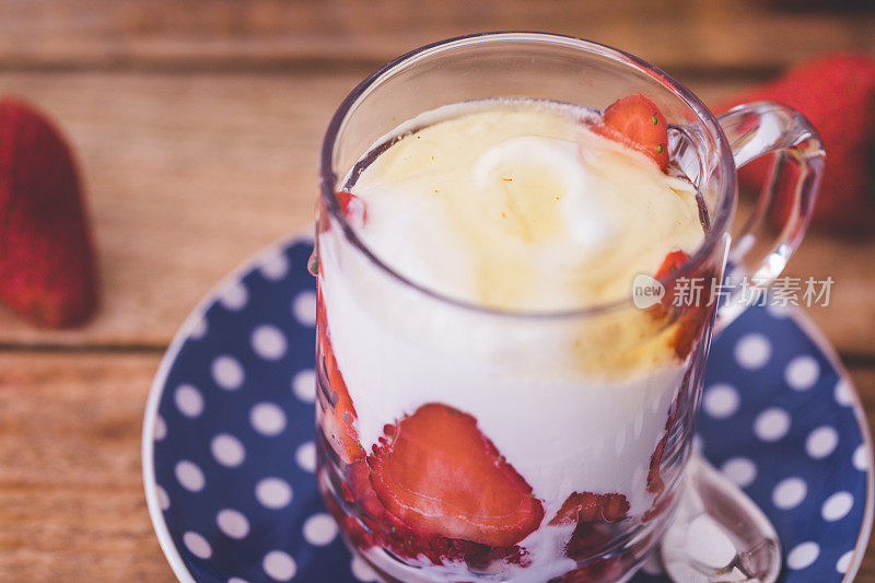 玻璃杯里的新鲜草莓配上希腊酸奶和蜂蜜，特写