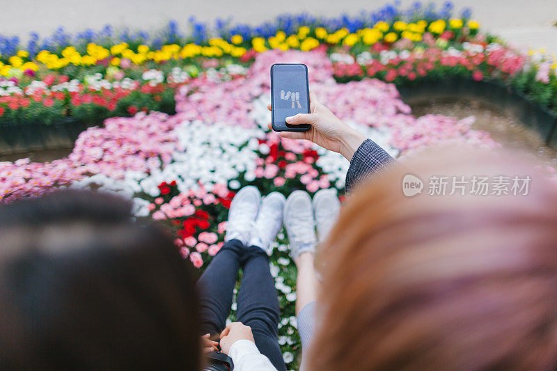 两个年轻女子正在用智能手机拍照