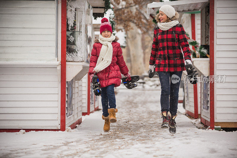 愉快的母亲和女儿在滑冰后蹦蹦跳跳，面带微笑
