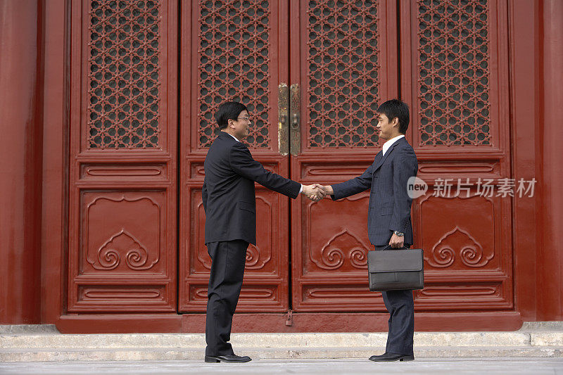 两位商务男士在太庙前握手