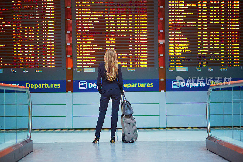 一位女士在国际机场看航班信息板