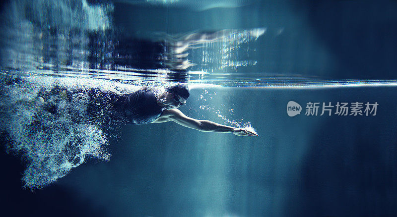运动员游泳自由泳在蓝色背景，水下视图