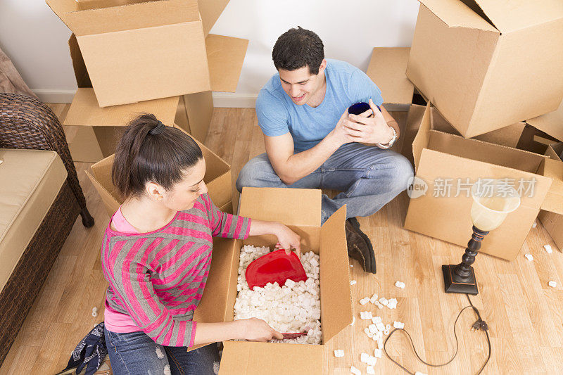 搬家:一对拉丁夫妇打开箱子。新家。