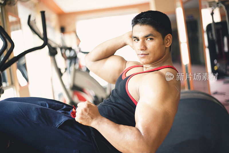 一个肌肉发达的年轻人在健身房里做仰卧起坐